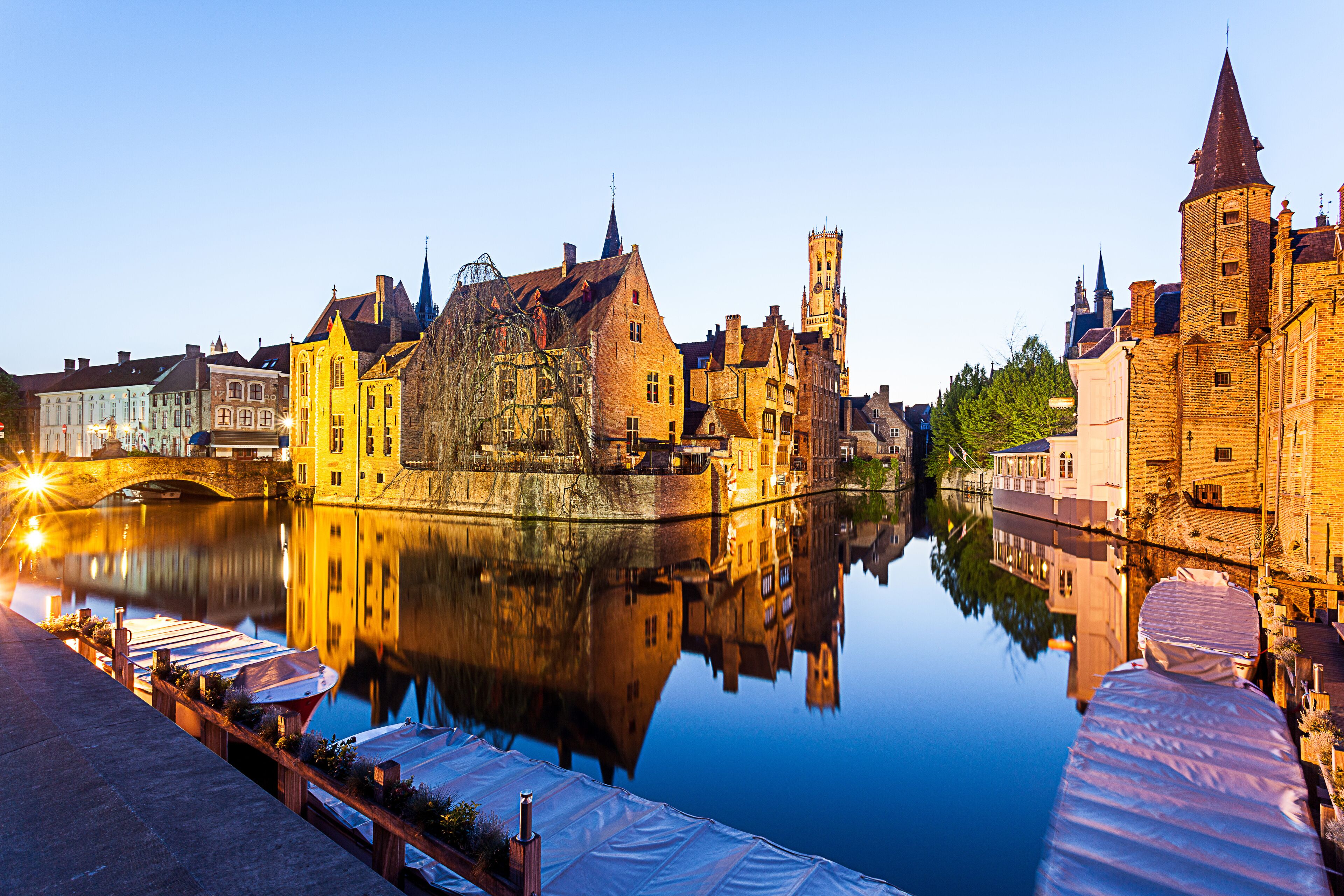 In Bruges at sunset during the blue hour, you see the refection of the building  and the tower