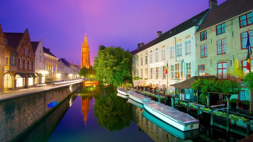 A canal with boats, a church spire, and historic buildings at twilight.