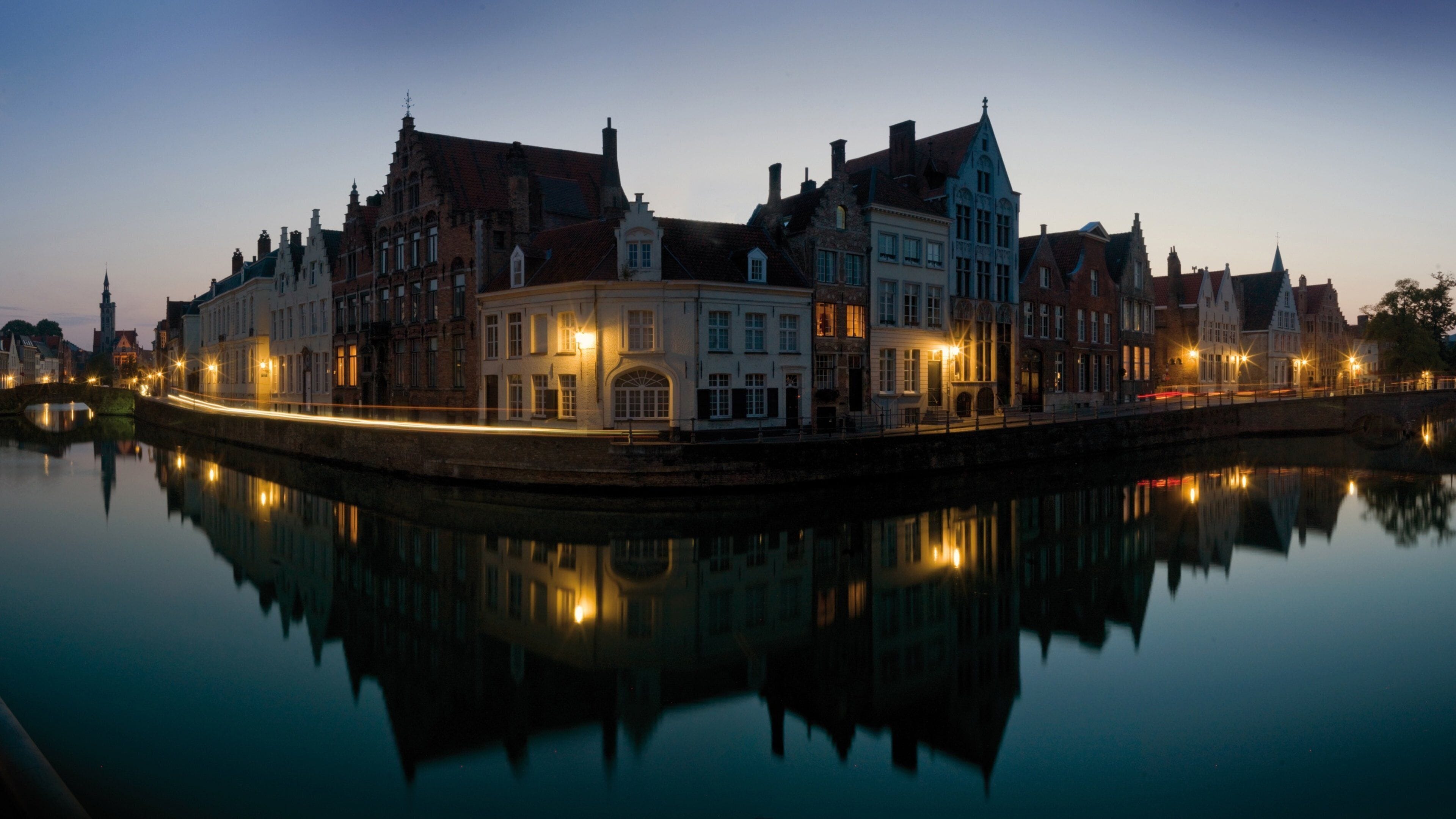A calm river reflecting historic buildings at dusk.
