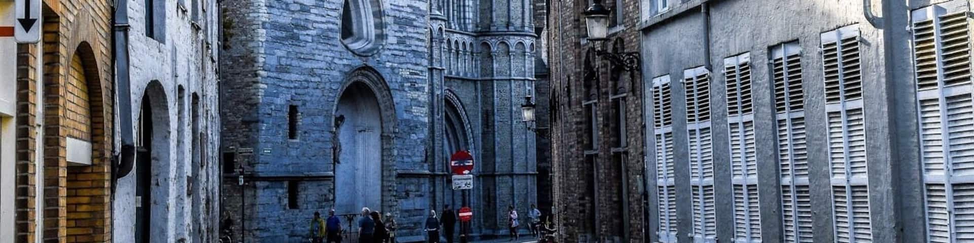 A cobblestone street leading to a historic church with pointed towers.