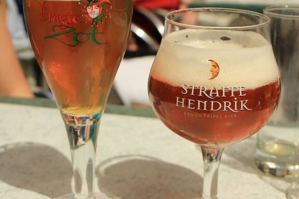 Deux verres à bière, chacun portant une étiquette : l’un indique « Brugs ZO » et l’autre « STRAFFE HENDRIK BRUGS TRIPEL BIER ».
