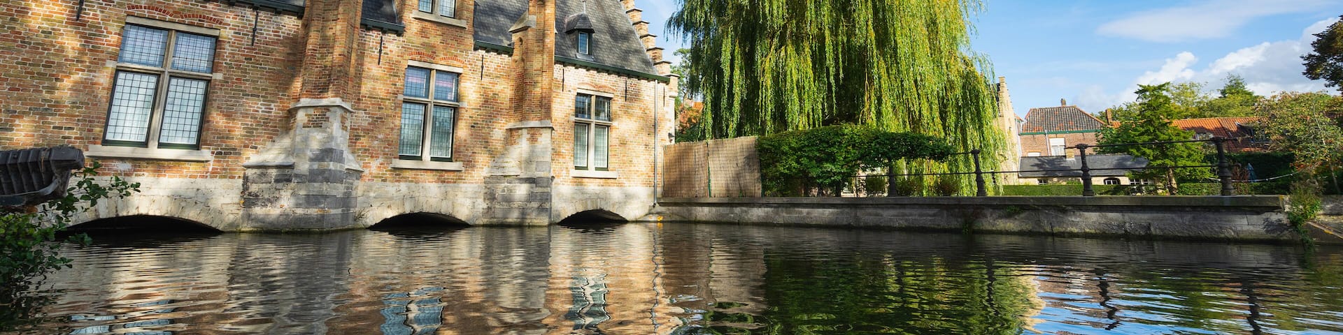 Beautiful ancient building and tree at the canal in Brugge. Belgium. Banner edition.
