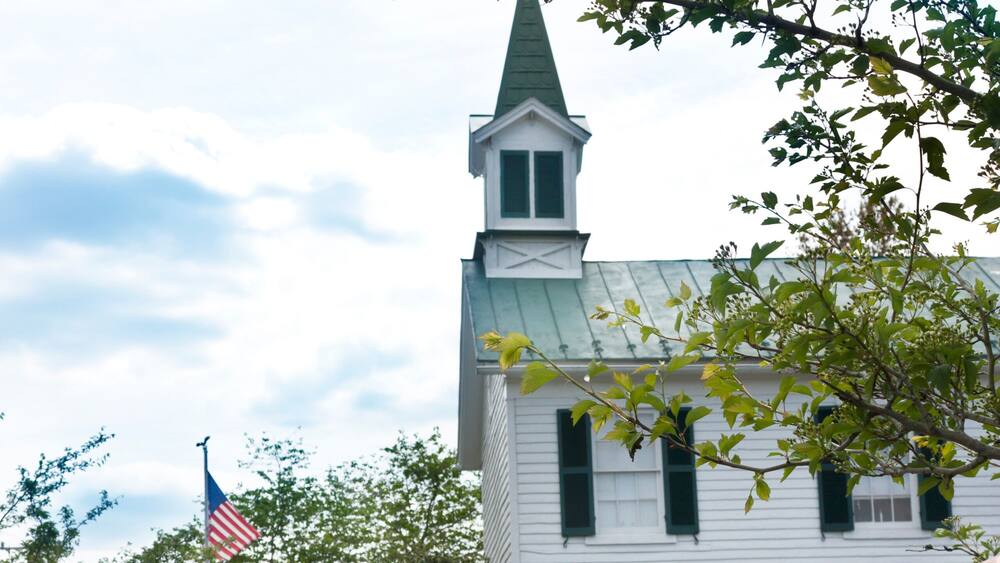 A sign for The Town of Haymarket with a church in the background.