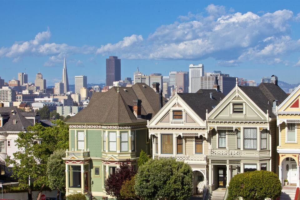 Casas victorianas en una ciudad con un horizonte en el fondo.