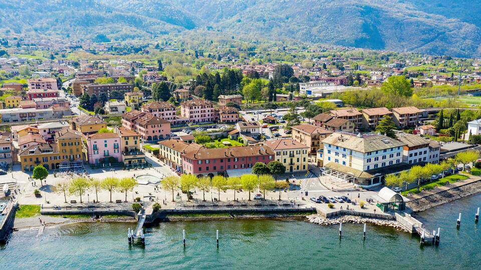 A riverside town with historic buildings, a bridge, and mountains in the background.