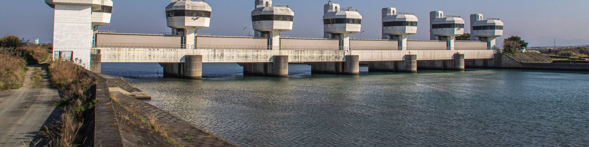A concrete bridge with multiple cylindrical structures spanning a body of water.