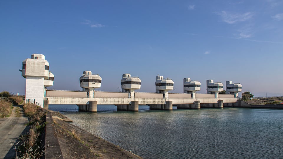 A concrete bridge with multiple cylindrical structures spanning a body of water.