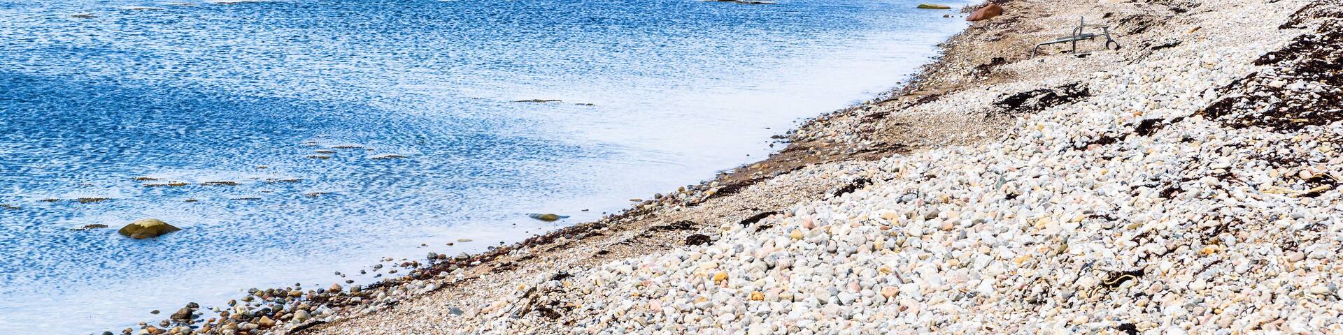 Coastal landscape outside Nyhamnslage in Skane, Sweden, with a stony beach in the bay and a distant cliff headland.