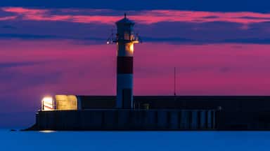 Farol ao anoitecer com céu rosa e roxo.