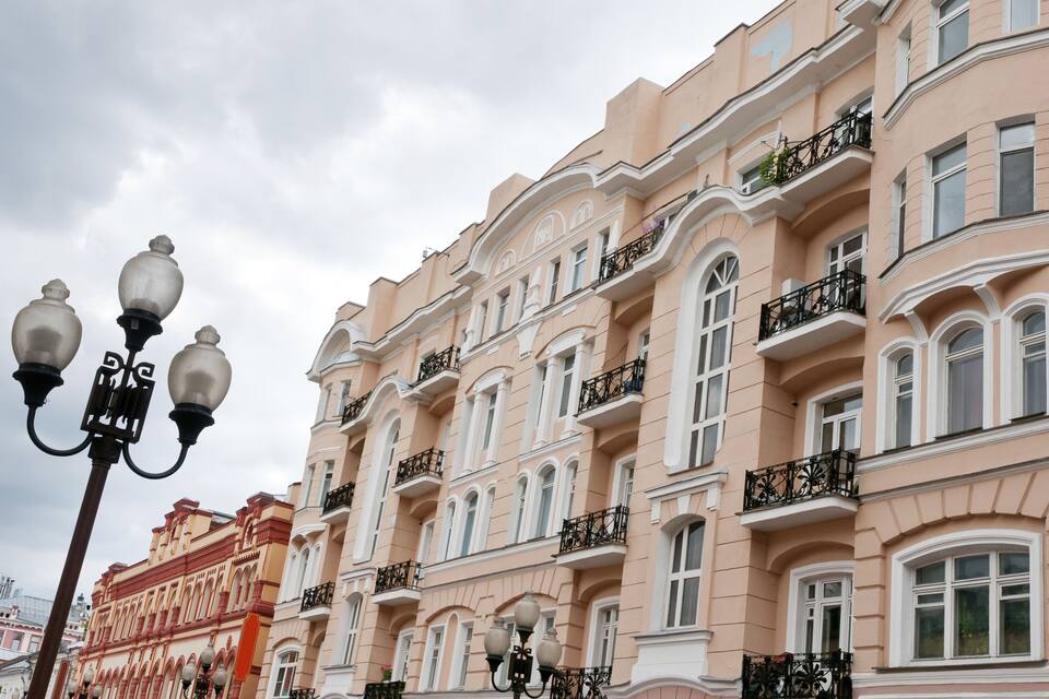 A multi-story pink building with ornate balconies and arched windows.