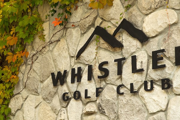 A stone wall with the text "WHISTLER GOLF CLUB" and a logo above it.