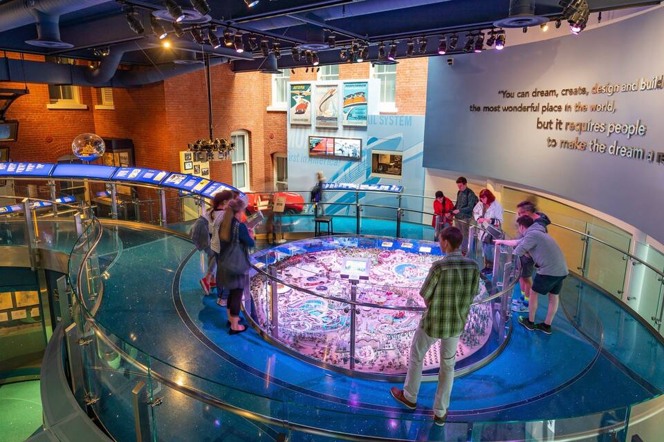 A museum exhibit with a large circular display, informational panels, and a quote on the wall.