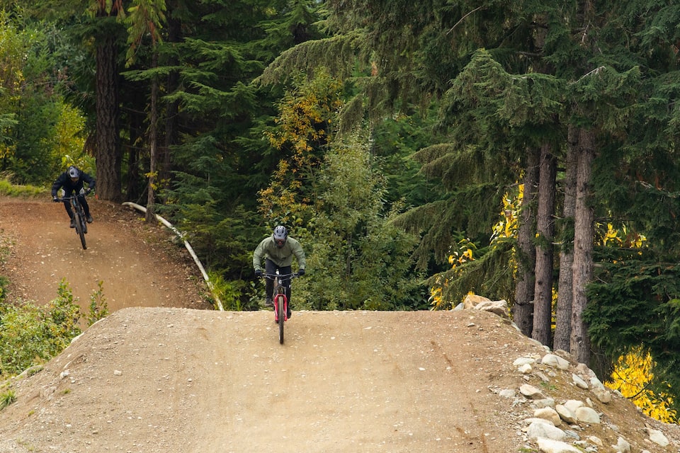 A mountain biking trail surrounded by dense forest and rocky terrain.