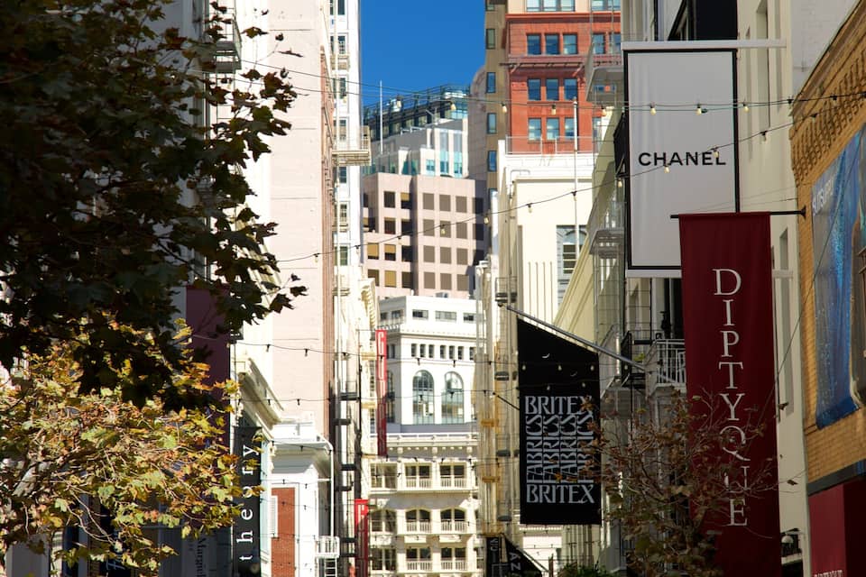 Un carrer urbà amb edificis alts, incloent una botiga Chanel i una botiga BRITEX.
