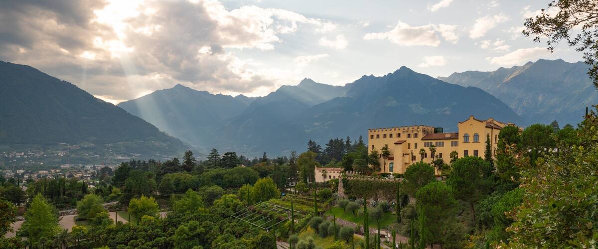 Un château entouré d’une végétation luxuriante et de montagnes.