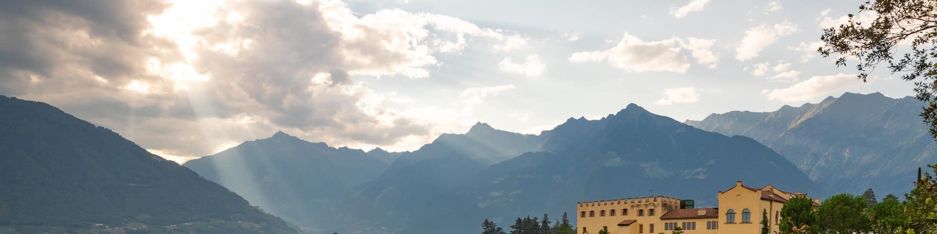 A castle surrounded by lush greenery and mountains.