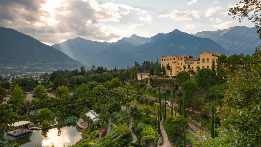 A castle surrounded by lush greenery and mountains.