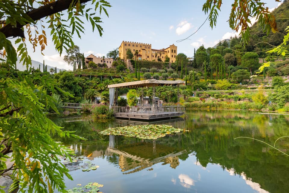 A serene lake with lily pads, a wooden dock, and a castle in the background.