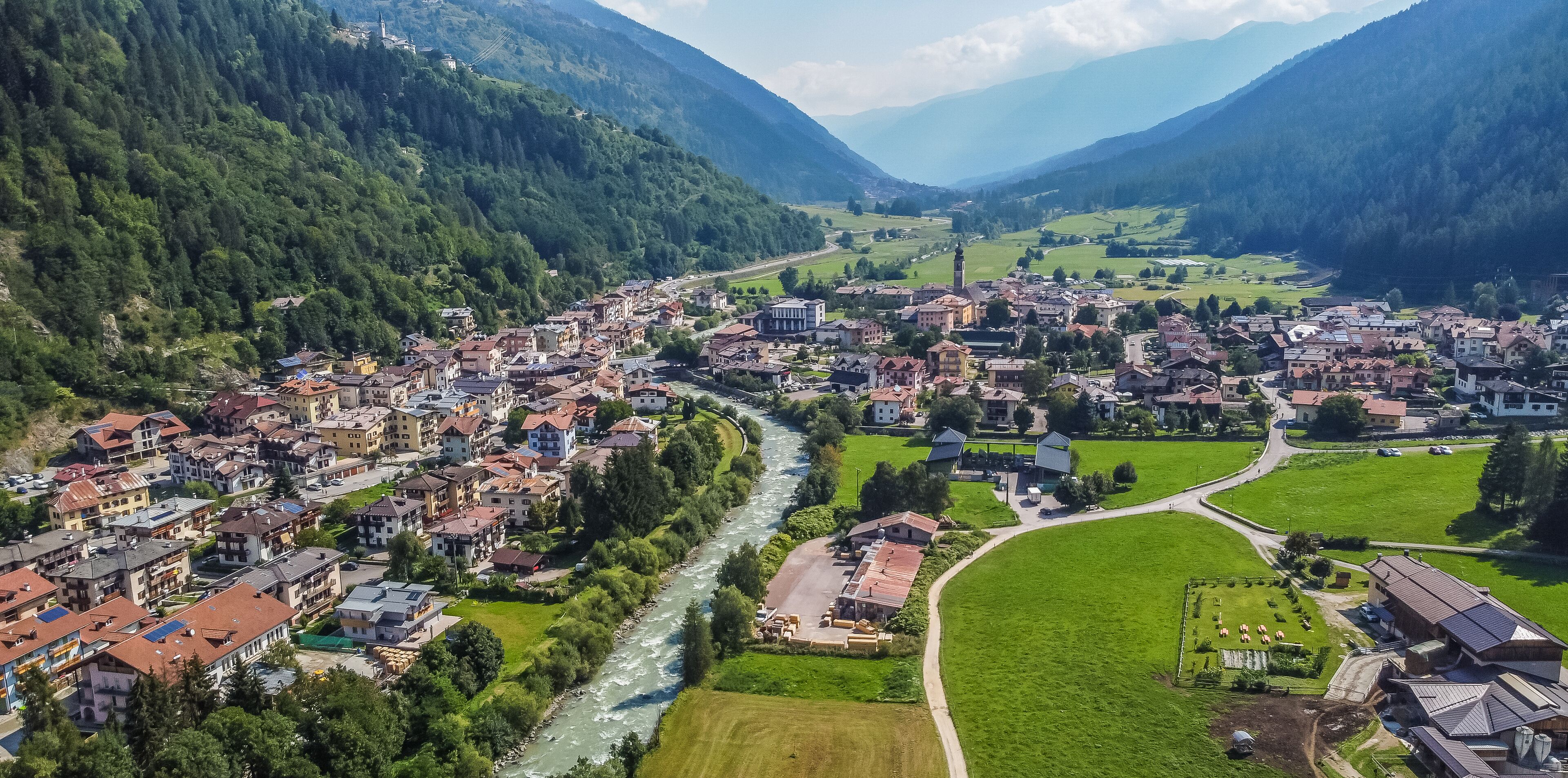 A town nestled in a valley with a river running through it, surrounded by mountains.
