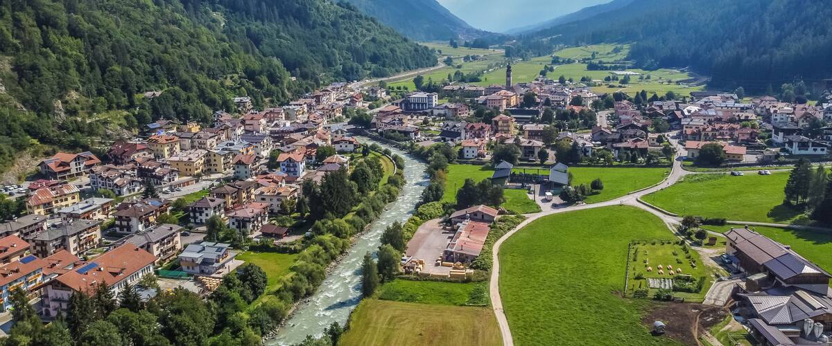 A town nestled in a valley with a river running through it, surrounded by mountains.