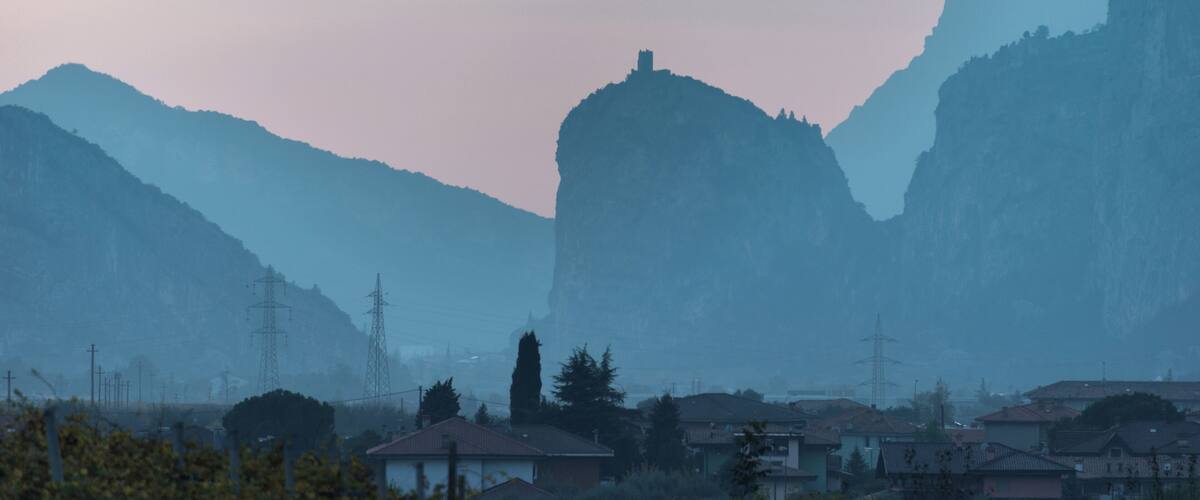 A mountainous landscape with a village in the foreground and a large rock formation in the background.