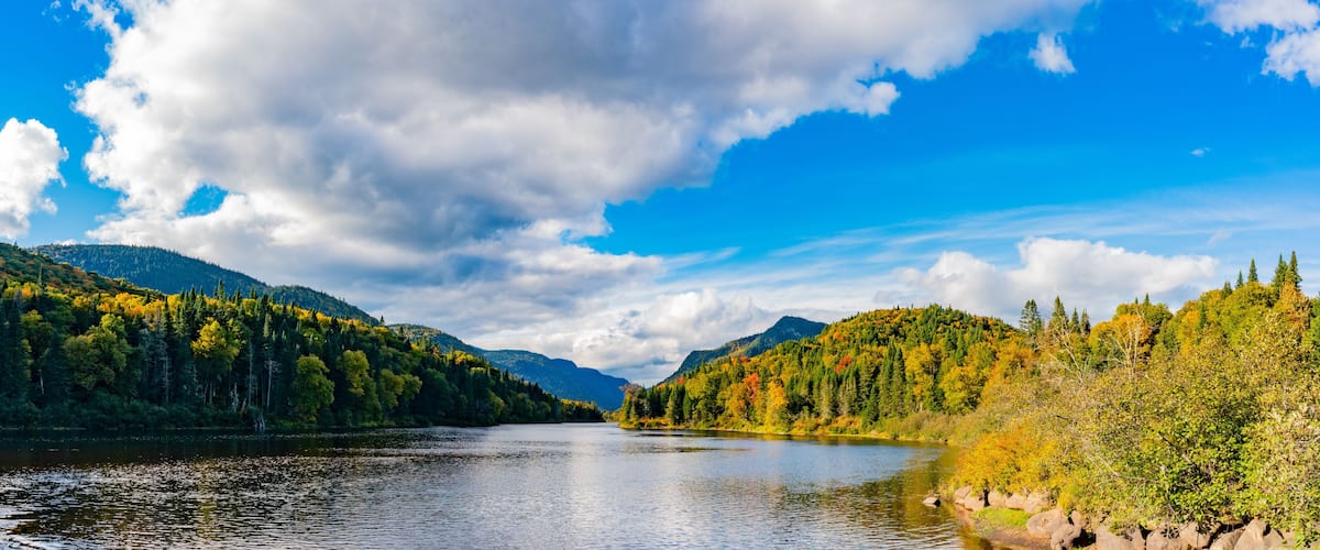 A calm lake surrounded by forested hills with autumn foliage.