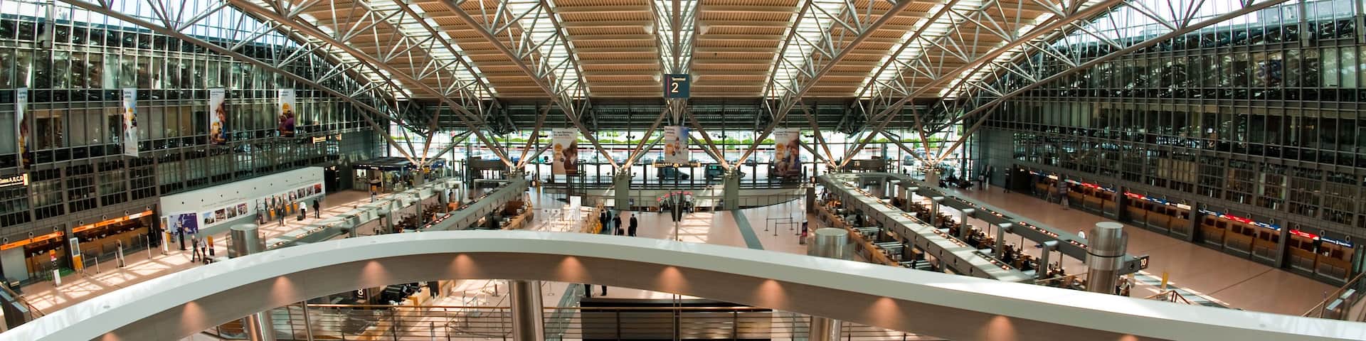 A spacious indoor area with a high ceiling and large windows, featuring a central open space and multiple levels.