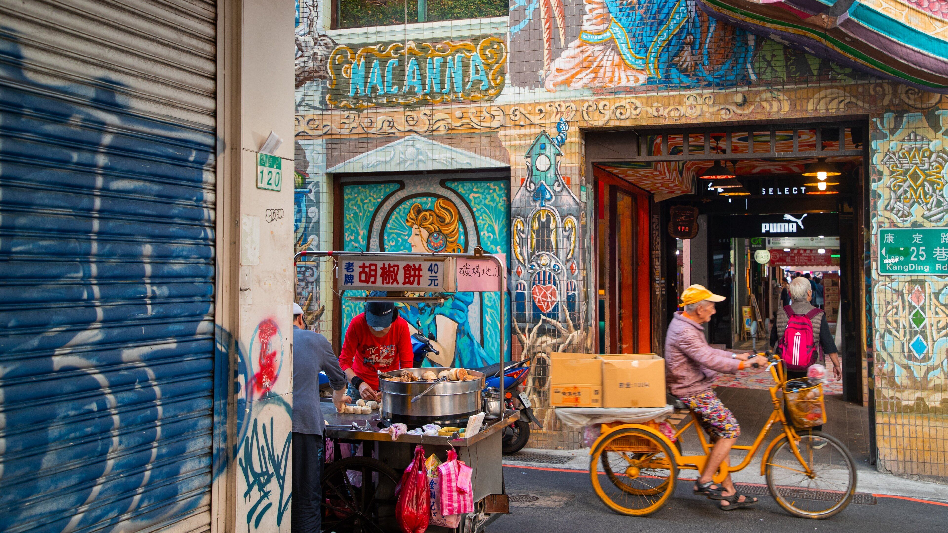 A street scene with a food cart, a mural, and a storefront.
