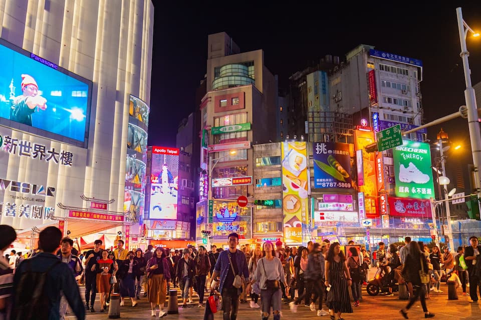 A bustling night scene with illuminated billboards and crowded streets.