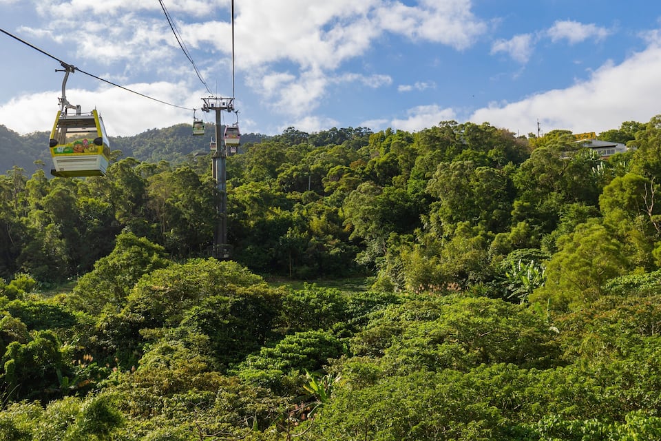 A cable car system amidst lush green forested hills.