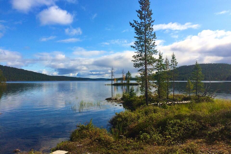 A calm lake surrounded by forested hills.