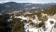 Un paysage montagneux enneigé, avec une route sinueuse et de vastes forêts.