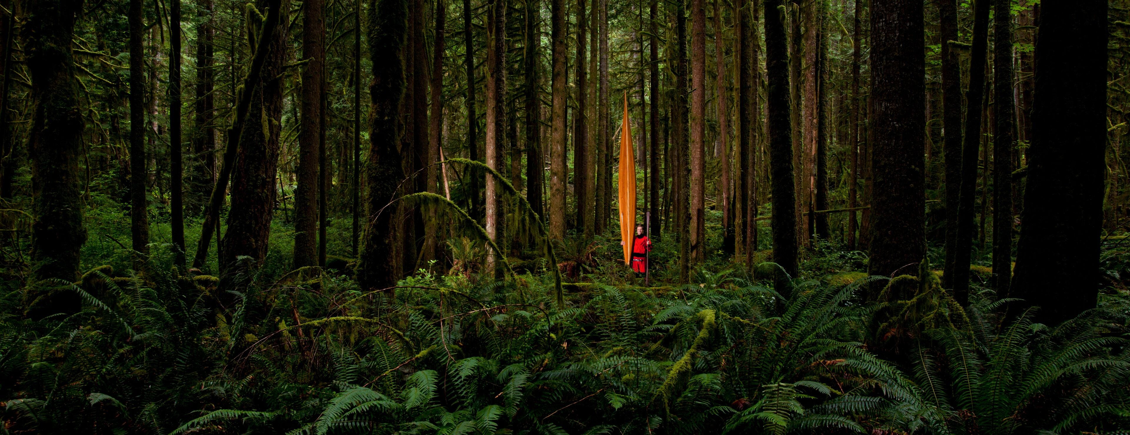 Portrait of a man in a dry suite with his hand-made Cedar Strip Kayak in a temperate rain forest.