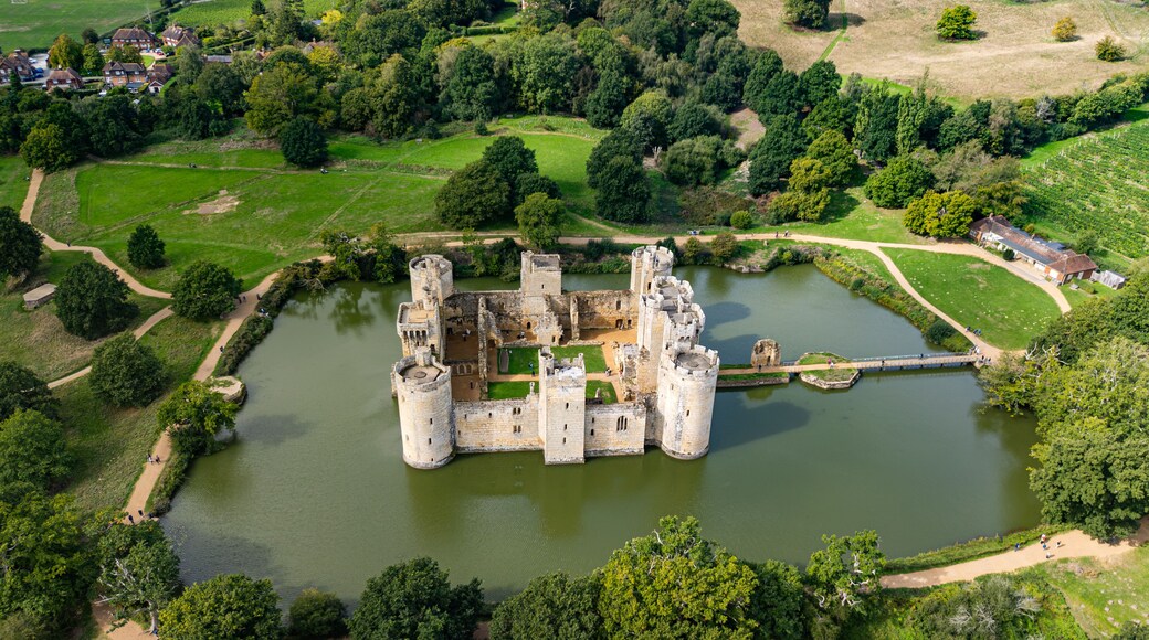 High aerial view of the 14th-century moated Bodiam Castle surrounded by water, green lawns, and woodland near Robertsbridge in East Sussex, England
