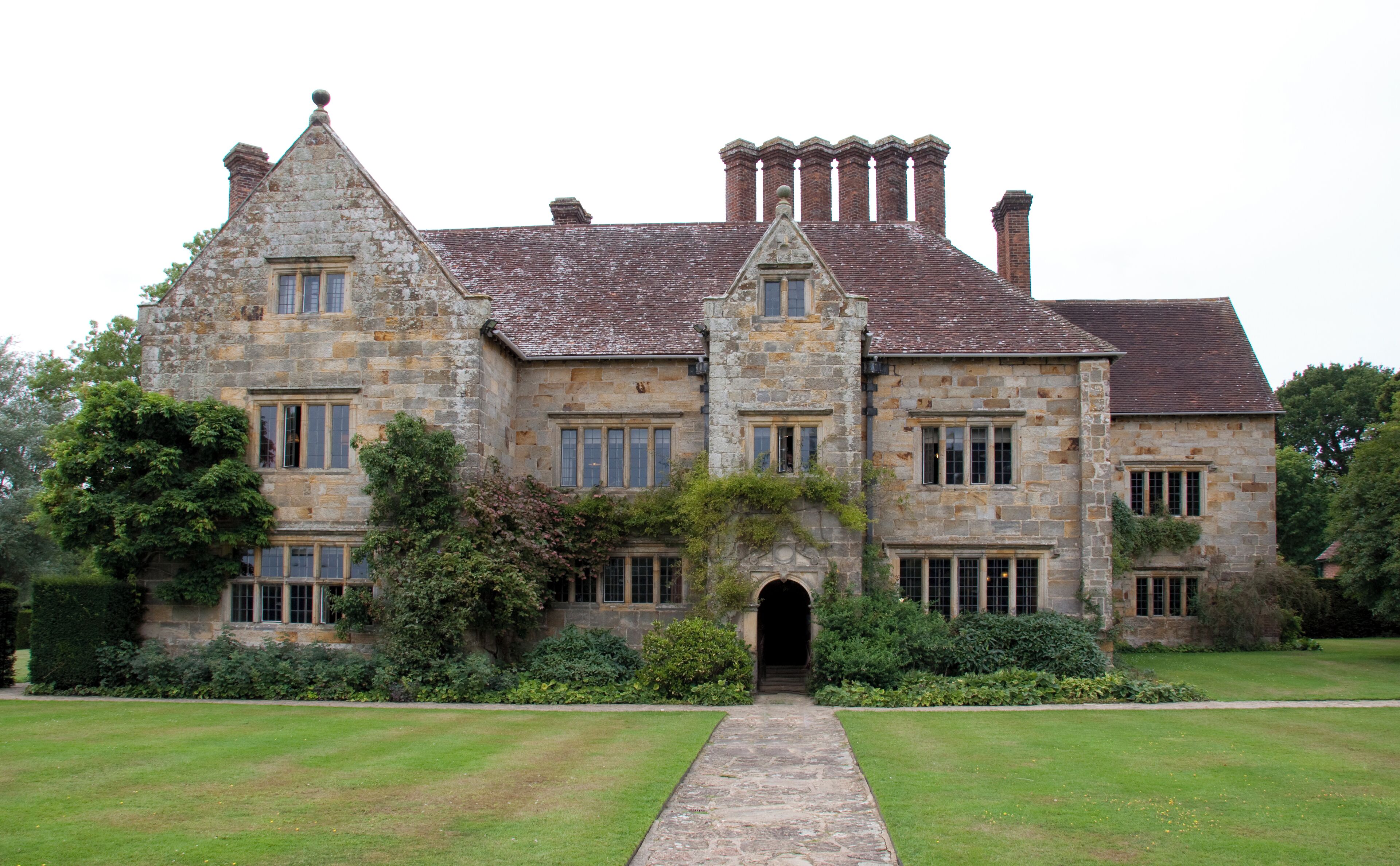 A large stone building with multiple chimneys and a central archway.