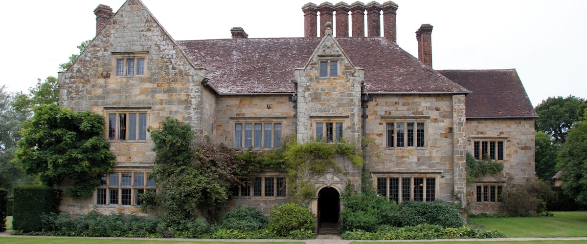 A large stone building with multiple chimneys and a central archway.