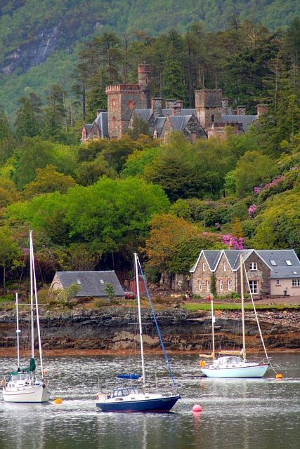 A coastal village with sailboats, a castle, and lush greenery.