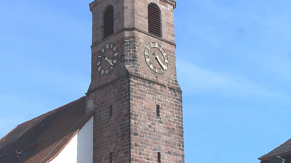 A historic clock tower with a weather vane on top, set against a clear blue sky.