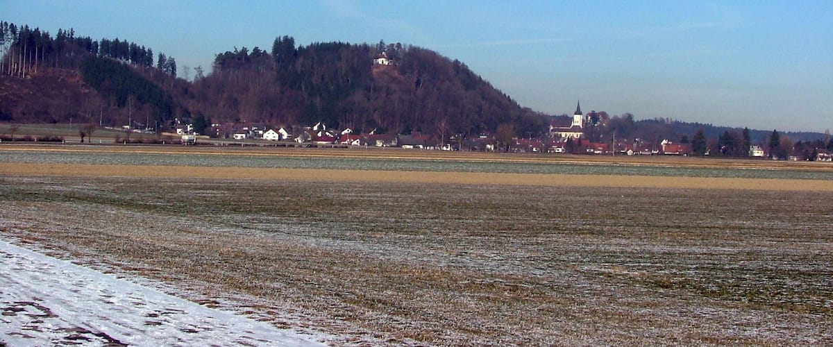 A rural landscape with a hill, houses, and a church.