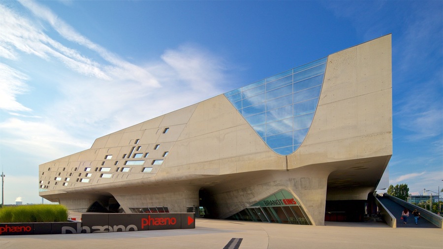 A modern architectural building with a unique angular design, featuring a glass facade and a prominent entrance.
