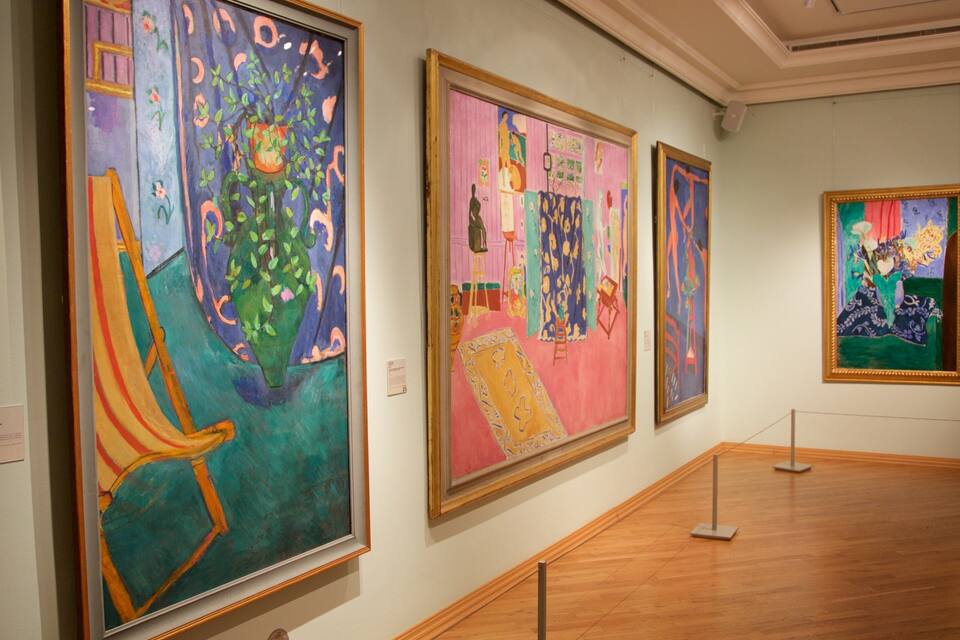 Una galleria con tre grandi quadri esposti al muro.