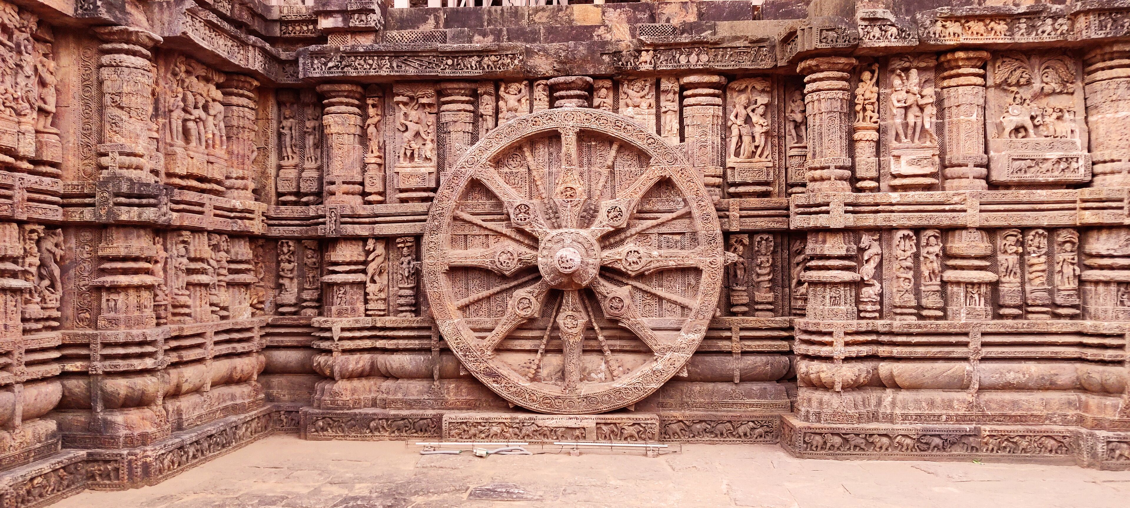 A large, intricately carved stone wheel with detailed carvings on the surrounding walls.