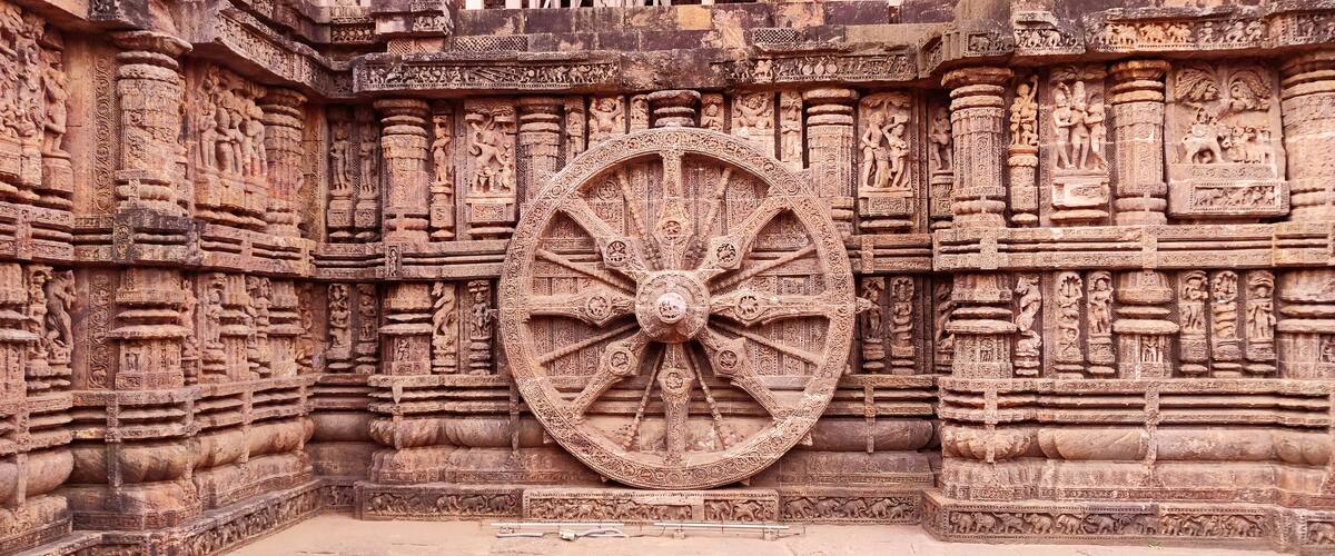 A large, intricately carved stone wheel with detailed carvings on the surrounding walls.