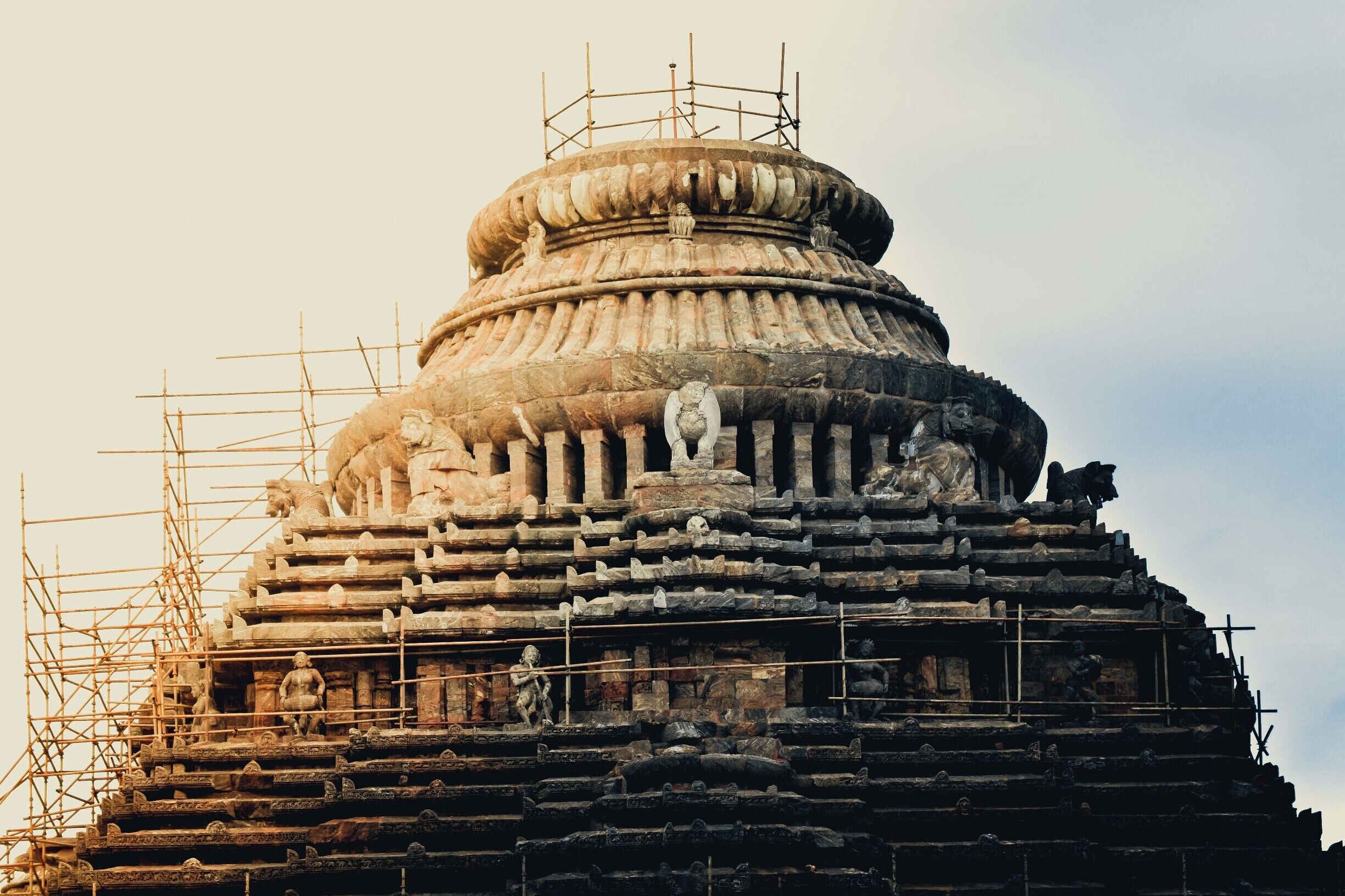 Konark Sun Temple is a 13th-century CE Sun Temple at Konark in Orissa, India. It is believed that the temple was built by king Narasimhadeva I of Eastern Ganga Dynasty[2] in 1255 CE.[3] The temple complex is in the shape of a gigantic chariot, having elaborately carved stone wheels, pillars and walls. A major part of the structure is now in ruins. The temple is a UNESCO World Heritage Site[4] and has also featured on various list of Seven Wonders of India. The temple is 35 km from Puri and 65 km from Bhubaneswar.
The name Konark derives from the combination of the Sanskrit words, Kona (corner or angle) and Ark (the sun), in reference to the temple which was dedicated to the Sun God Surya.[4]

The monument was also called the Black Pagoda'(Kaala Pagoda) by the European sailors. In contrast, the Jagannath Temple in Puri was called the White Pagoda. Both temples served as important landmarks for the sailors.[5] Konark Sun Temple used Iron beams for its structure.
The temple was originally built at the mouth of the river Chandrabhaga, but the waterline has receded since then. The temple has been built in the form of a giant ornamented chariot of the Sun god, Surya. It has twelve pairs of elaborately carved stone wheels which are 3 meters[4] wide and is pulled by a set of seven horses (4 on the right and 3 on the left).[6] The temple follows the traditional style of Kalinga architecture. It is carefully oriented towards the east so that the first rays of sunrise strikes the principal entrance.[4] The temple is built from Khondalite rocks.[7][8]

The original temple had a main sanctum sanctorum (vimana), which was supposedly 229 feet[6] (70 m) tall. Due to the weight of the superstructure (70 m tall) and weak soil of the area, the main vimana fell in 1837.[9] The audience hall (Jagamohana), which is about 128 feet (39 m) tall, still stands and is the principal structure in the surviving ruins. Among the structures, which have survived to the current day, are the dance hall (Nata mandira) and dining hall (Bhoga mandapa).[4][6]

The Konark temple is also known for its erotic sculptures of maithunas.[10]

Two smaller ruined temples have been discovered nearby. One of them is called the Mayadevi Temple and is located southwest from the entrance of the main temple. It is presumed to have been dedicated to Mayadevi, one of the Sun god's wives. It has been dated to the late 11th century, earlier than the main temple.[11] The other one belongs to some unknown Vaishnava deity. Sculptures of Balarama, Varaha and Trivikrama have been found at the site, indicating it to be a Vaishnavite temple. Both temples have their primary idols missing.

A collection of fallen sculptures can be viewed at the Konark Archaeological Museum which is maintained by the Archaeological Survey of India.