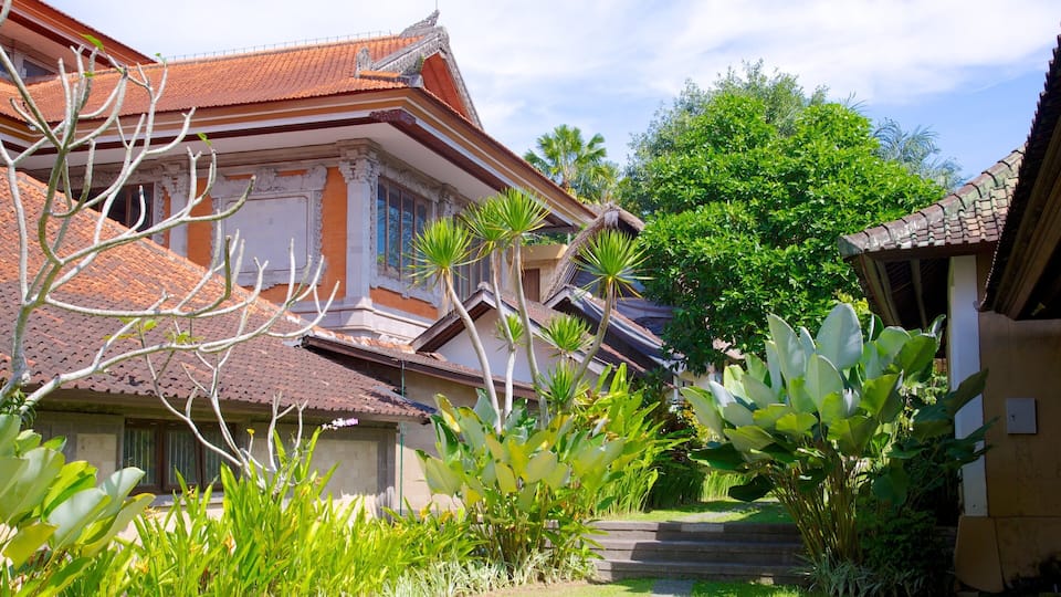 A traditional building with a tiled roof, surrounded by lush greenery and palm trees.