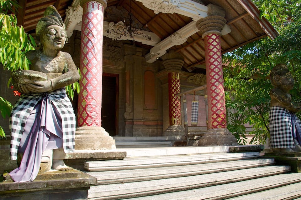 A temple with stone statues, red and white columns, and a covered entrance.