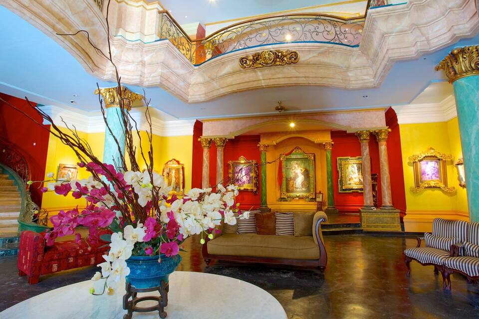A grand lobby with a staircase, ornate columns, and a large vase of orchids.