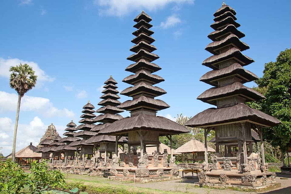 A temple complex with multiple tiered structures and thatched roofs.