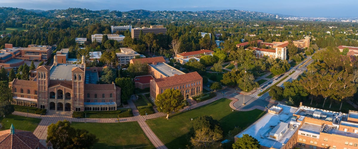 An aerial view of a university campus with historic buildings, green spaces, and a surrounding residential area.