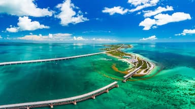 Un pont enjambant la côte et s’étendant sur des eaux turquoise, entouré d’un ciel dégagé et d’une terre lointaine.